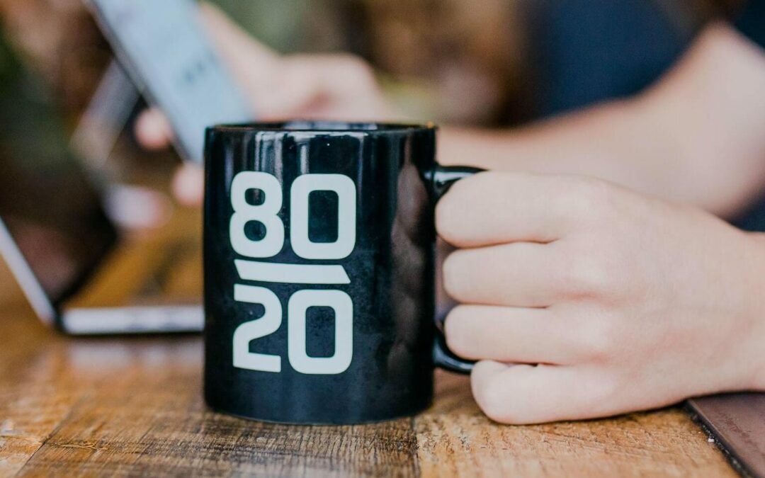 Person holding a mug with "80/20" on it