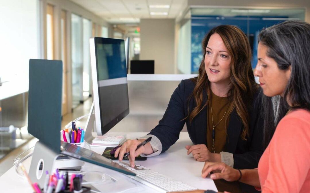 Two women work together on a computer at the office