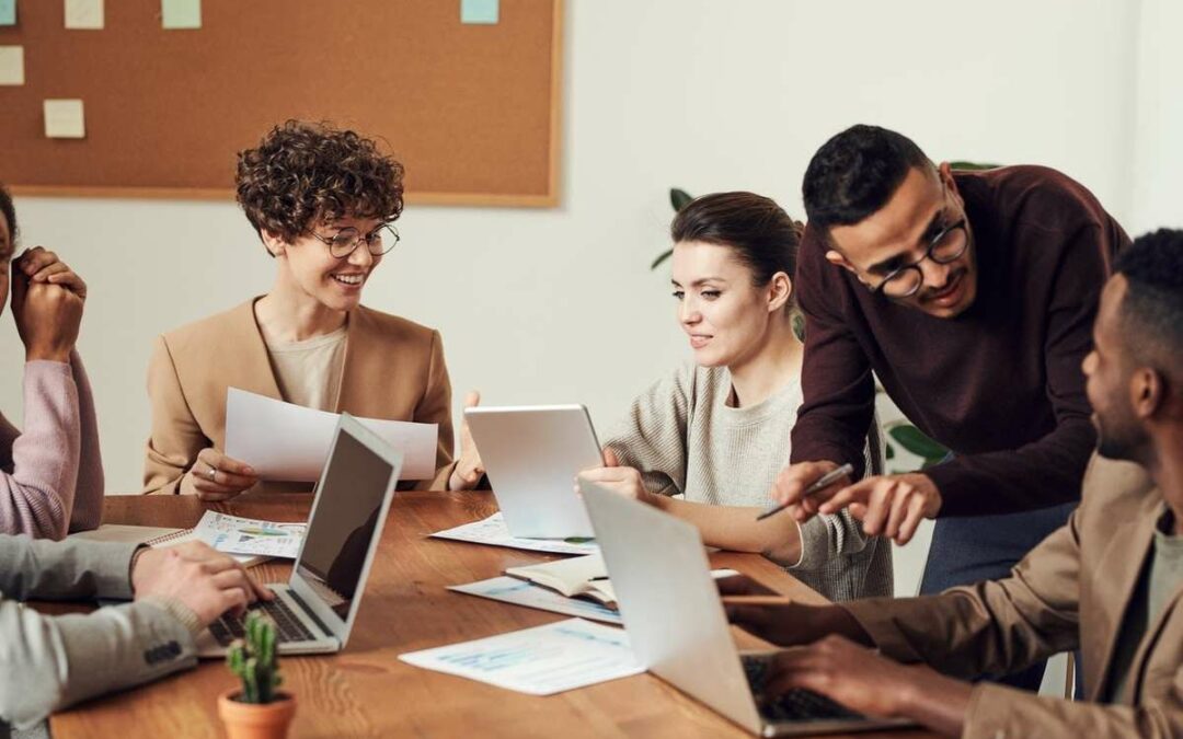 6 team members sitting round a table with open laptops https://www.pexels.com/photo/group-of-people-sitting-indoors-3184360/