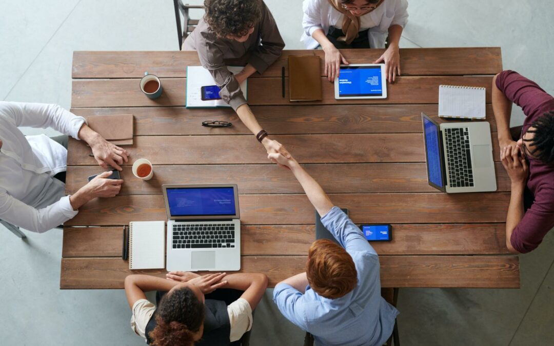 Group of people with laptops and notepads meeting at a table